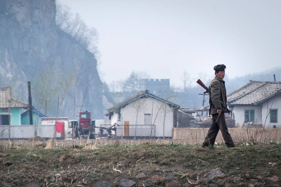一名朝鮮士兵在新義州附近的鴨綠江附近行走，對麵是中國邊境城市丹東。照片攝於4月份。