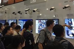 參觀人群在浙江大華技術股份有限公的展台觀看裝備人臉識別技術的攝像機的技術展示。