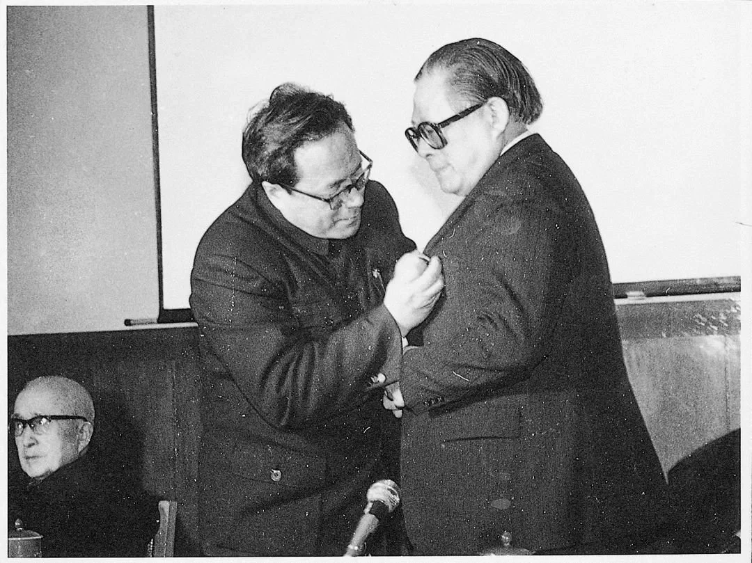 1989年3月，江澤民在上海交大教授聘任儀式上接受翁史烈校長佩戴校徽